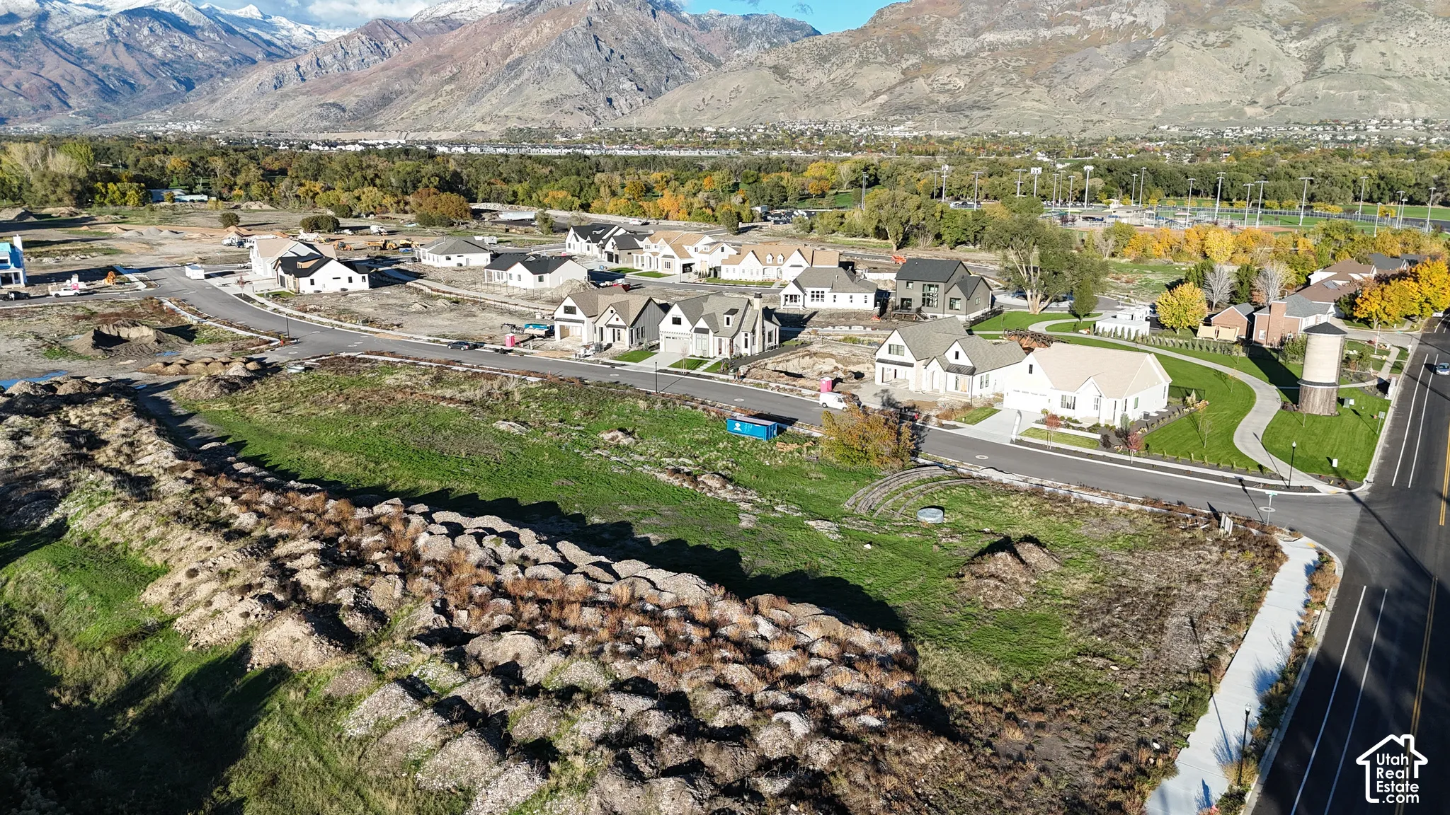 Undeveloped corner lot featuring asphalt street frontage, concrete sidewalks, and surrounding mountain scenery
