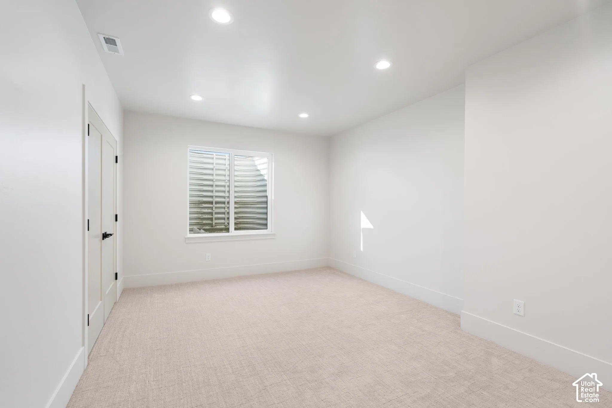 Neutral-toned carpeted flooring, recessed lighting, and double-door entry with matte black hardware