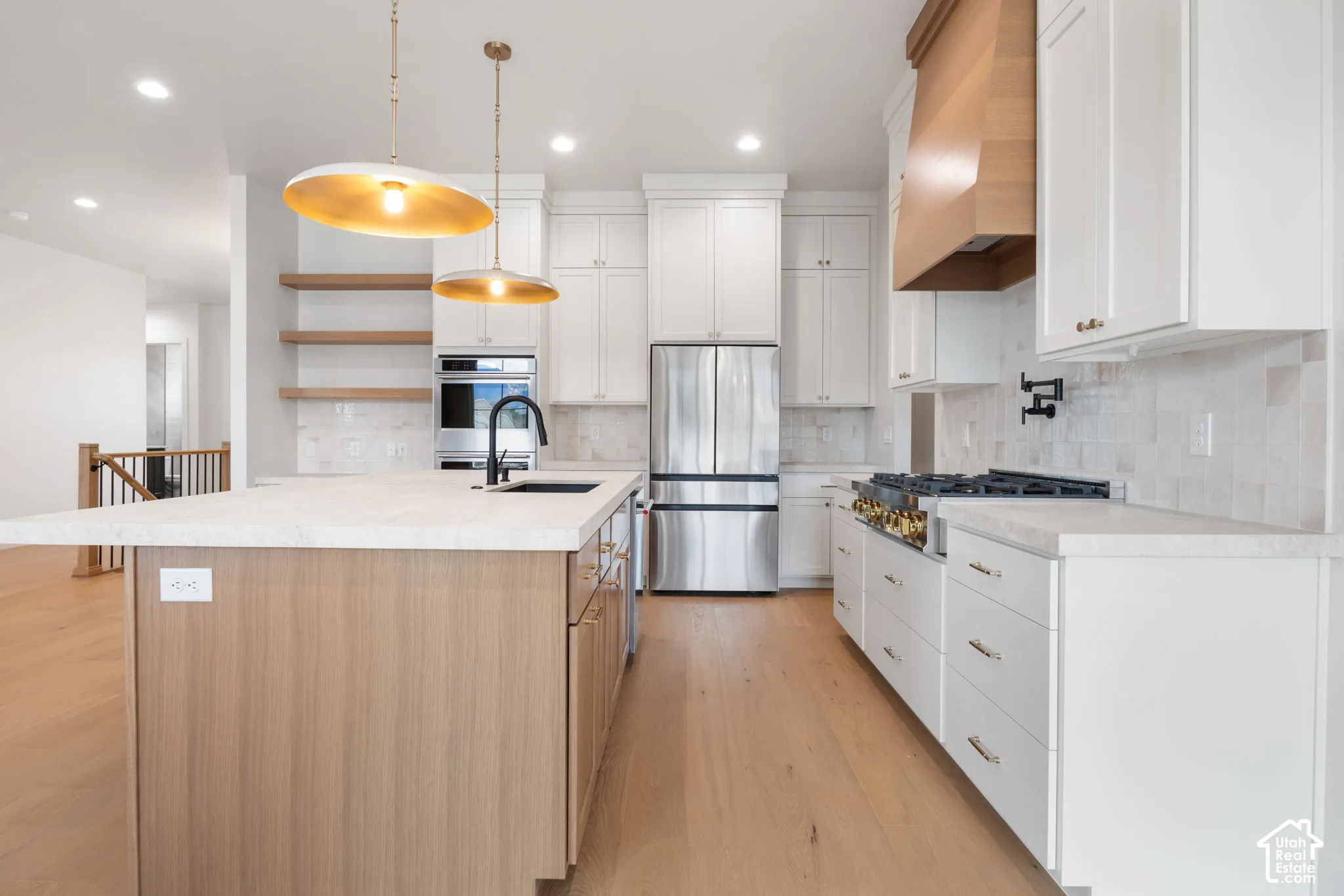 Kitchen featuring a wood-finish island, white cabinetry, a natural wood-finish range hood, stainless steel appliances, and wood-finish flooring