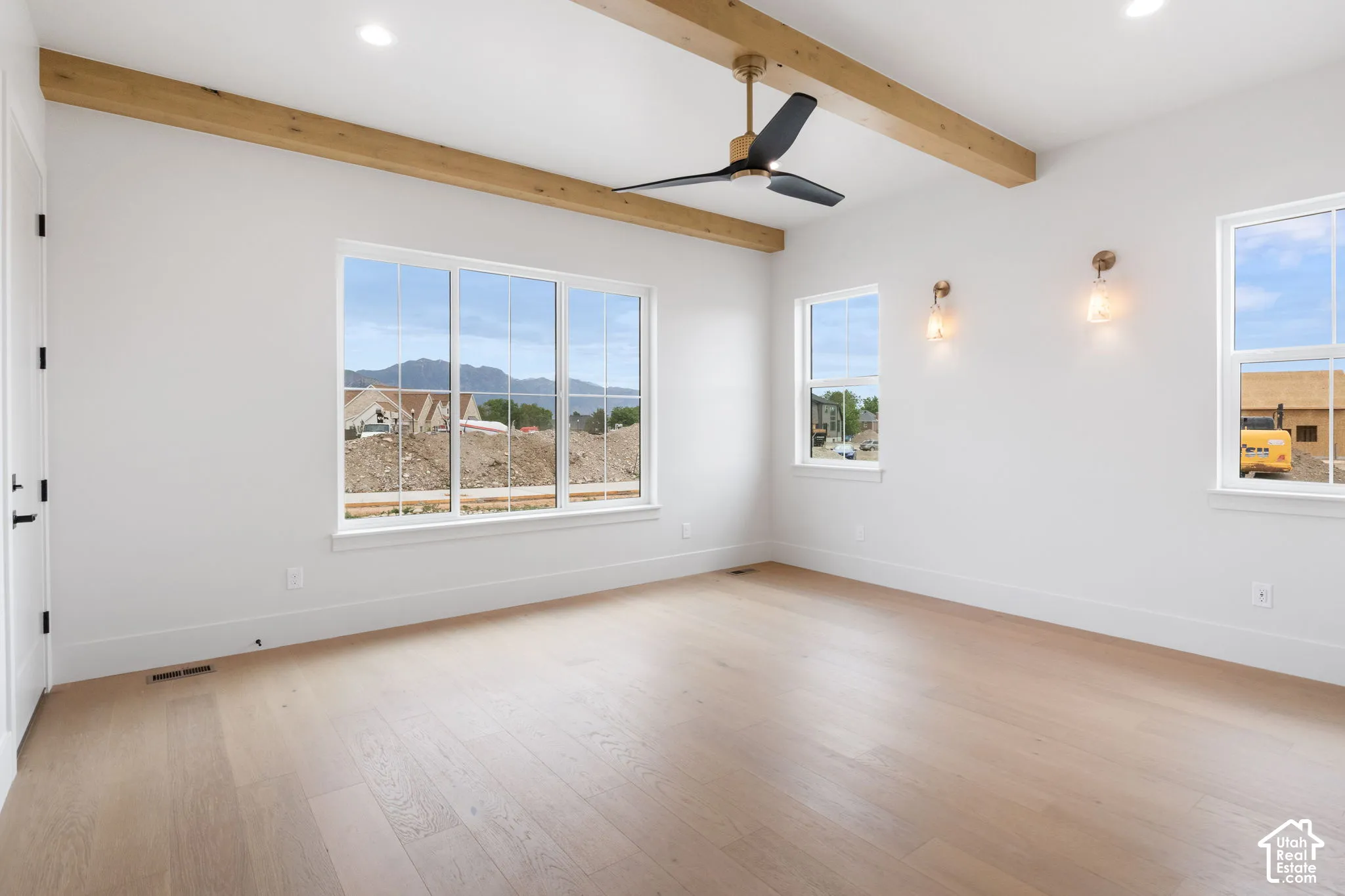 Wood-finish flooring, exposed timber ceiling beams, modern ceiling fan, recessed lighting, and wall-mounted sconces