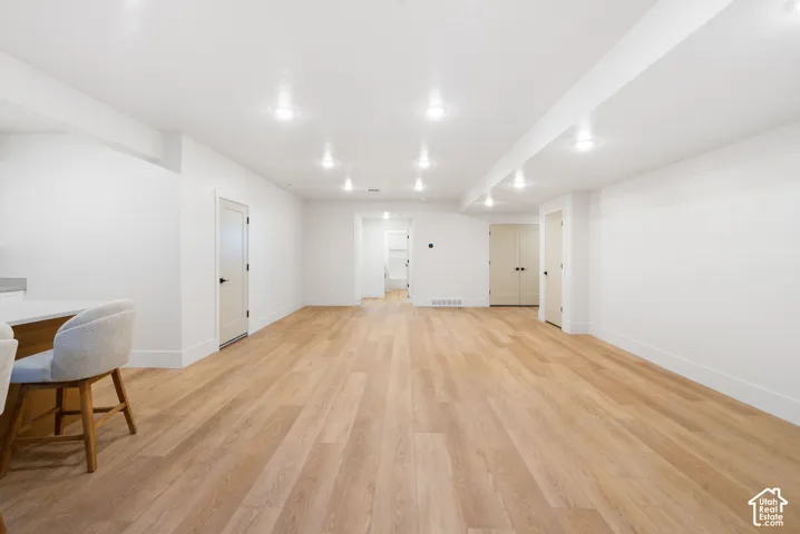 Expansive room featuring wood-finish flooring, recessed lighting, and multiple interior doors with matte black hardware