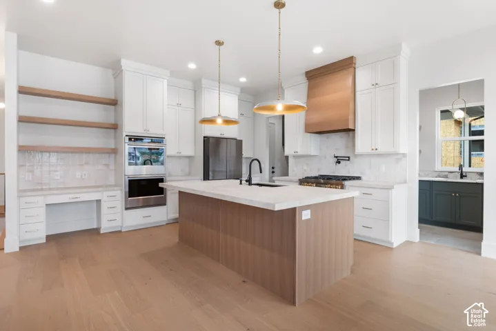 Kitchen featuring white shaker cabinetry, wood-finish center island, quartz countertops, stainless steel double wall oven, and built-in wood shelving