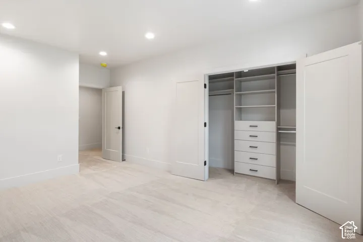 Room featuring neutral carpeting, recessed lighting, and a walk-in closet with built-in shelving and integrated drawer storage