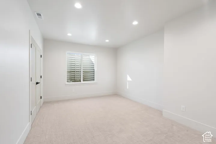 Neutral-toned carpeted flooring, recessed lighting, and double-door entry with matte black hardware