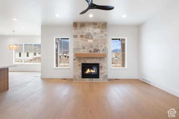 Floor-to-ceiling stone-clad fireplace featuring a wood mantel, wood-finish flooring, recessed lighting, and a modern ceiling fan