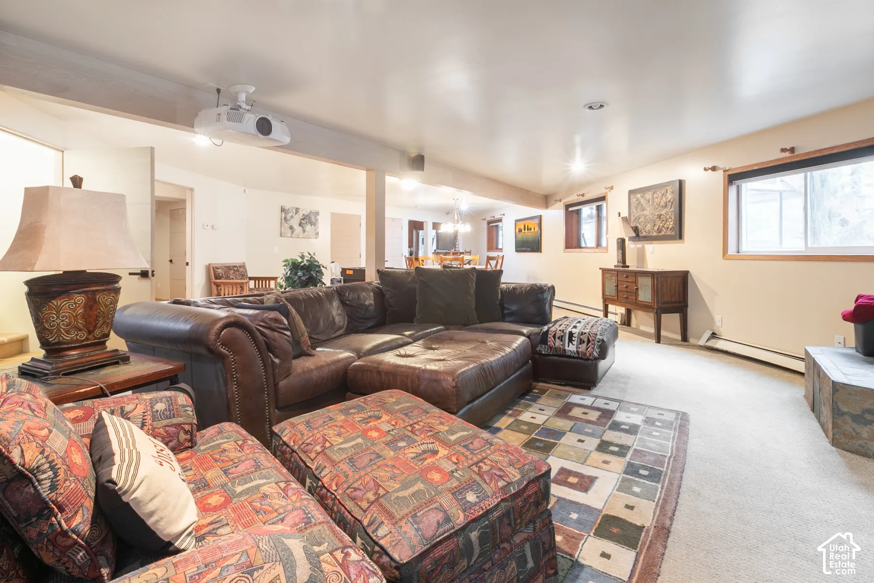 Open-concept interior featuring ceiling-mounted projection equipment, recessed lighting, neutral wall finishes, and a stone-clad hearth