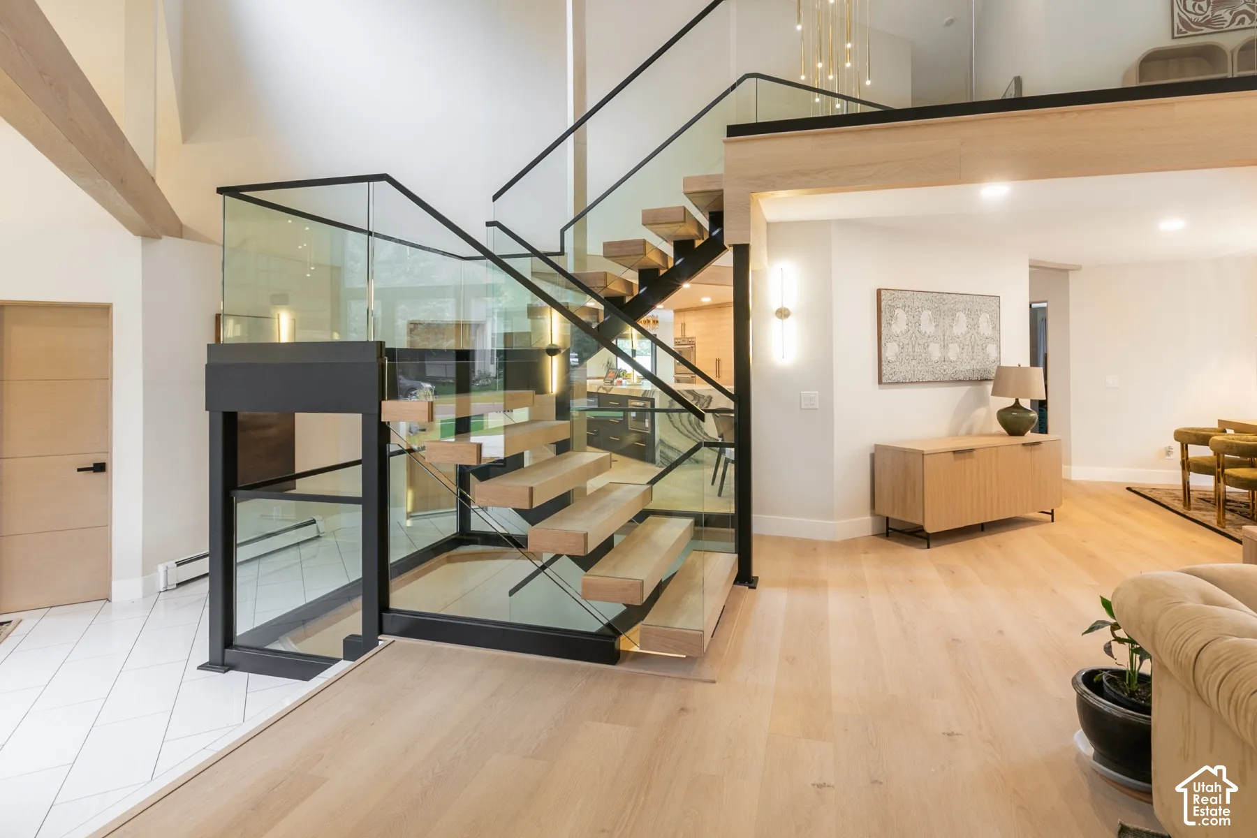 Open-riser staircase featuring natural wood treads, black metal stringers, and tempered glass railings with a matching black metal frame