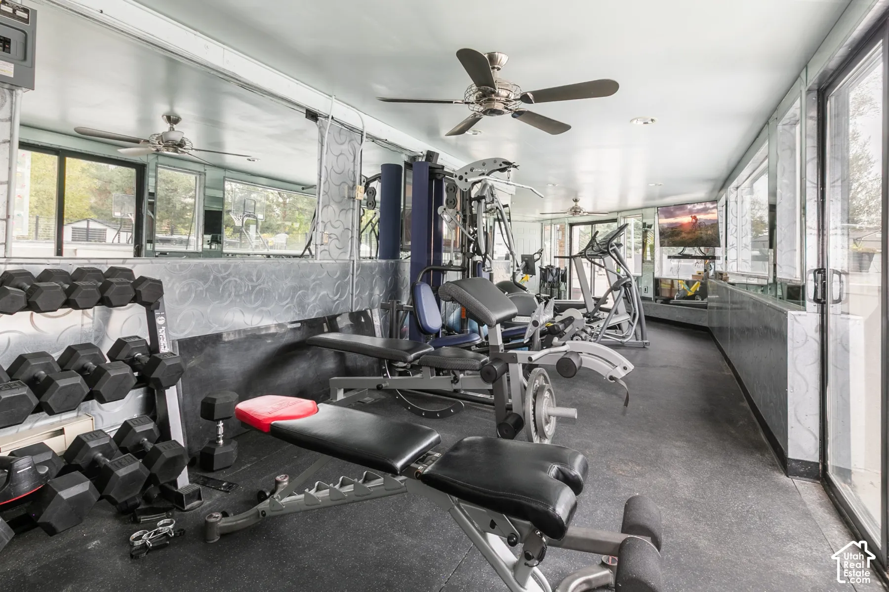 Recreational space featuring wall-to-wall mirrors, recessed lighting, ceiling fans, rubber flooring, and full-height glass sliding doors