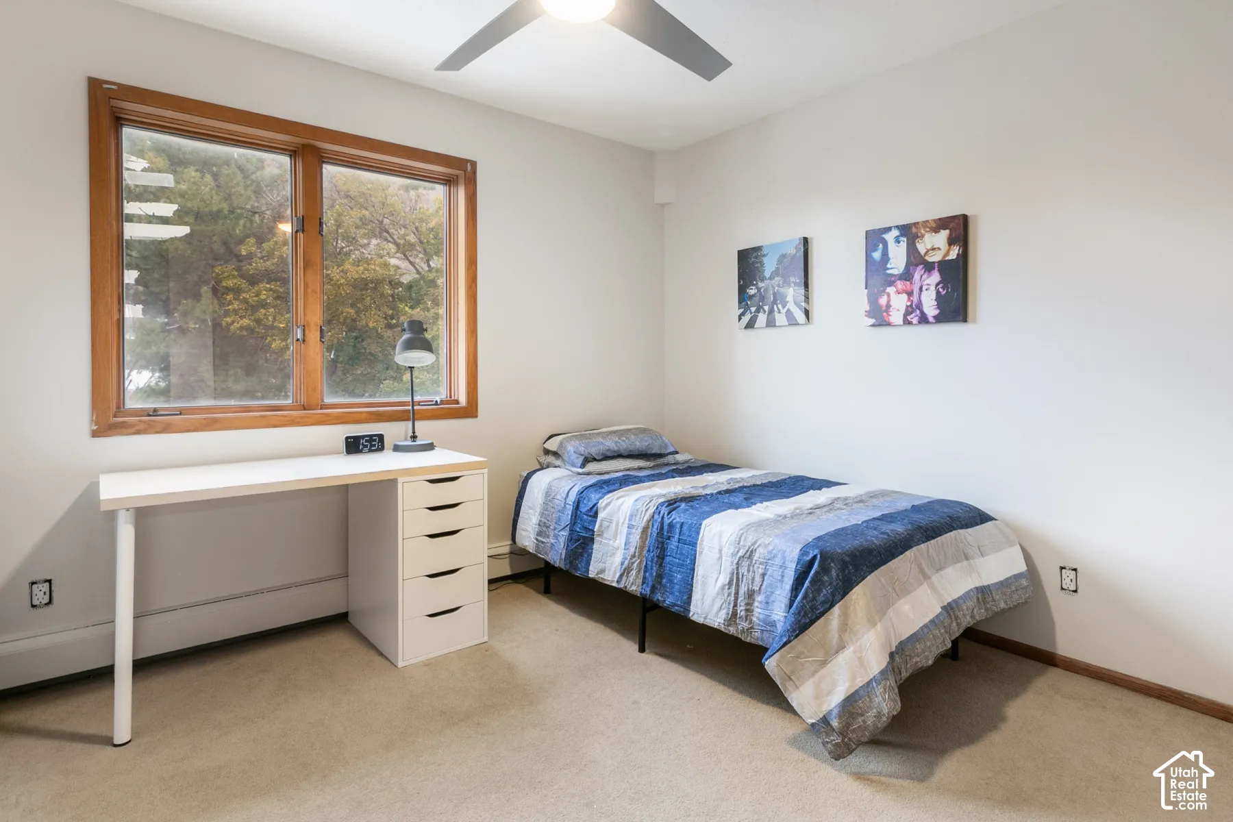 Neutral-toned room featuring a wood-trimmed window, ceiling fan with integrated lighting, and wall-to-wall carpeting