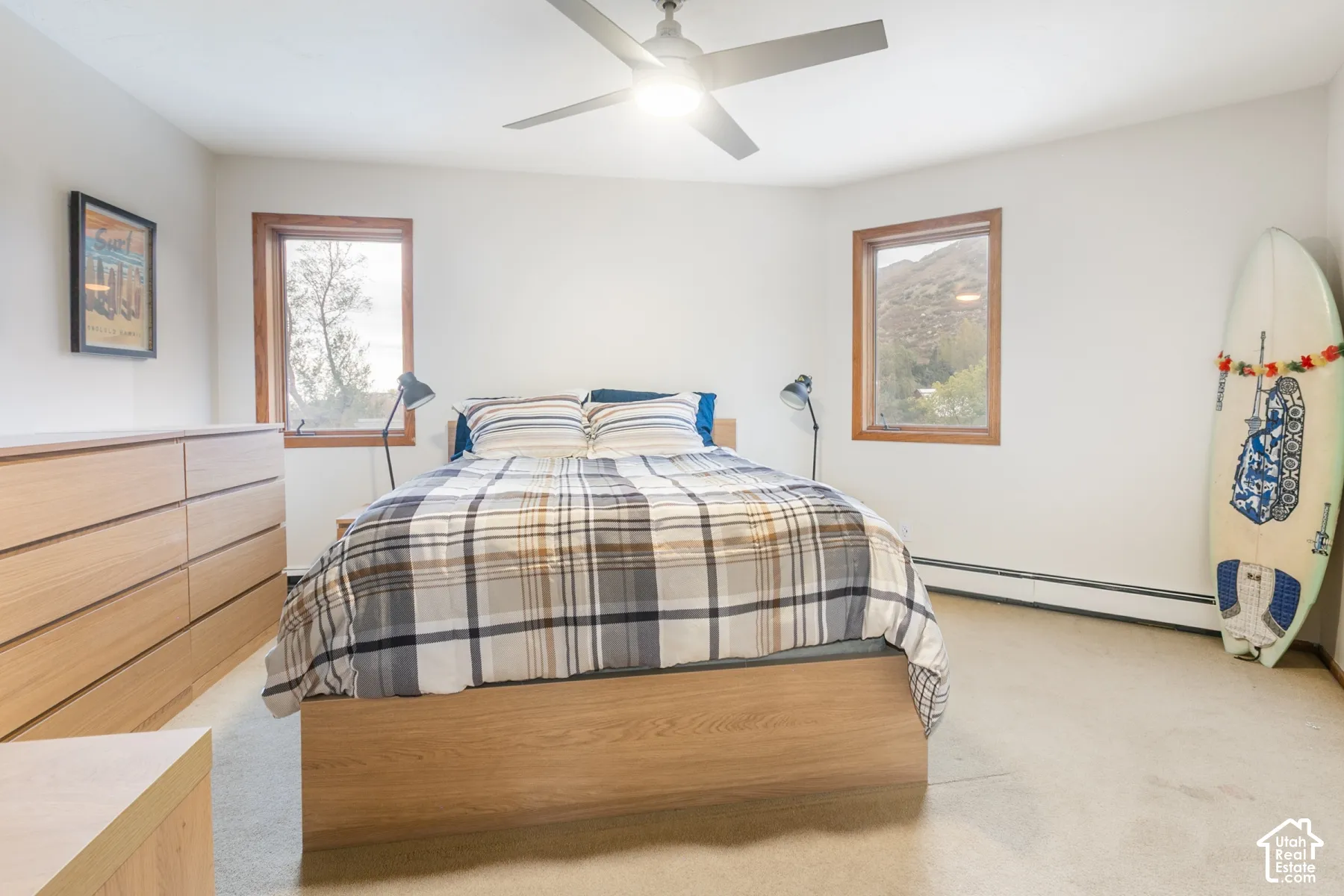 Bedroom featuring neutral-toned carpeting, wood-trimmed windows, a ceiling fan with integrated lighting, and mountain scenery