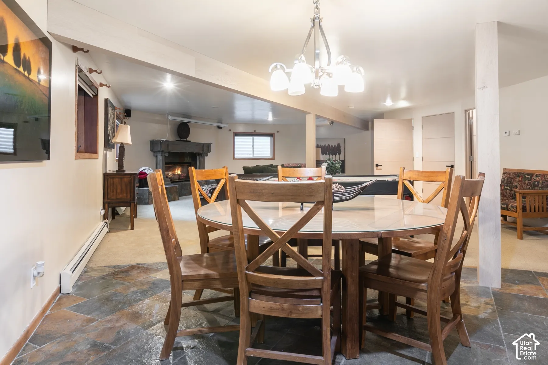Multi-use area featuring stone-tile flooring, a masonry fireplace, a multi-arm chandelier, and two paneled interior doors