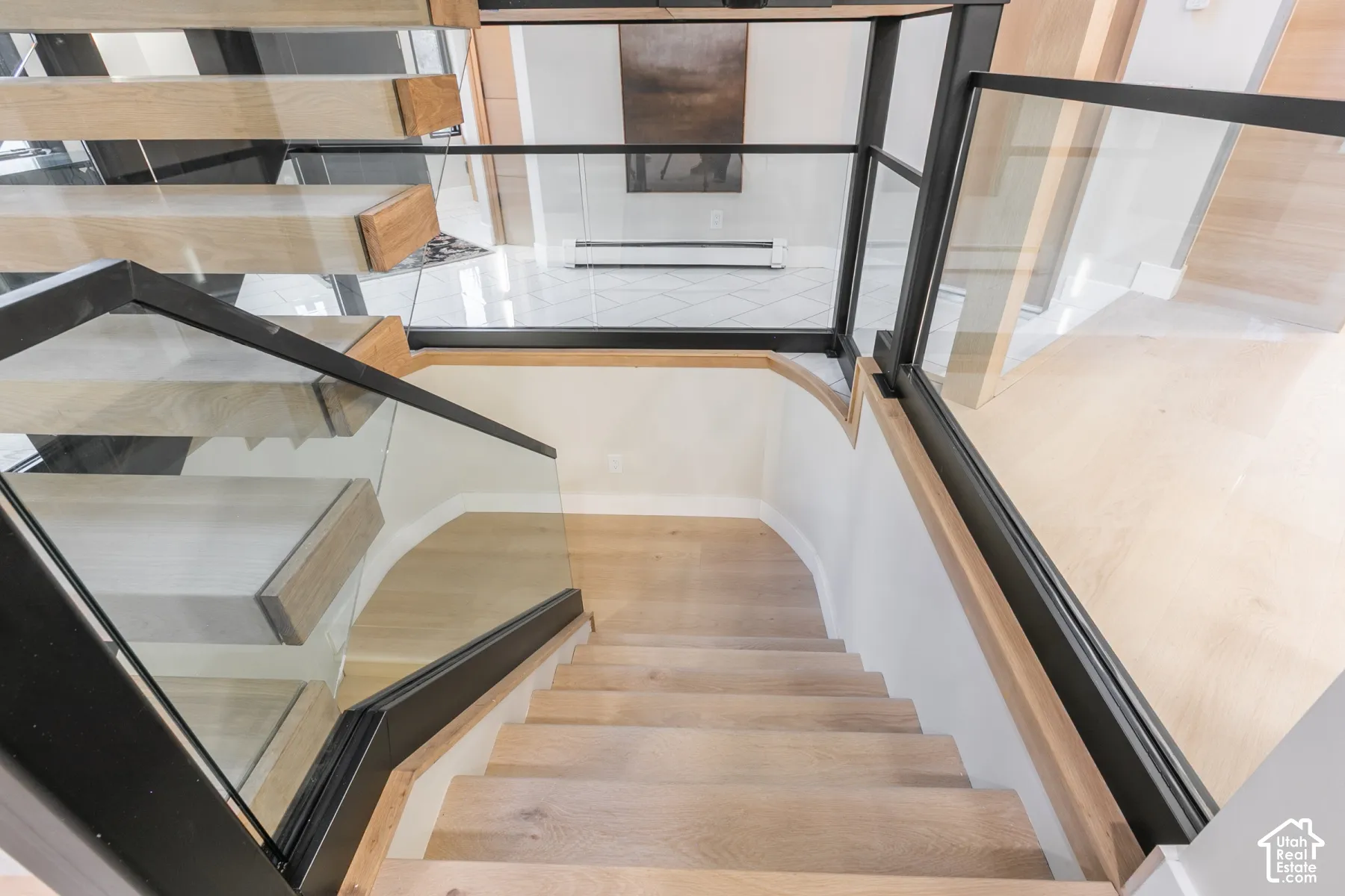 Open-riser staircase featuring natural wood-finish treads, structural black metal framing, and glass railings