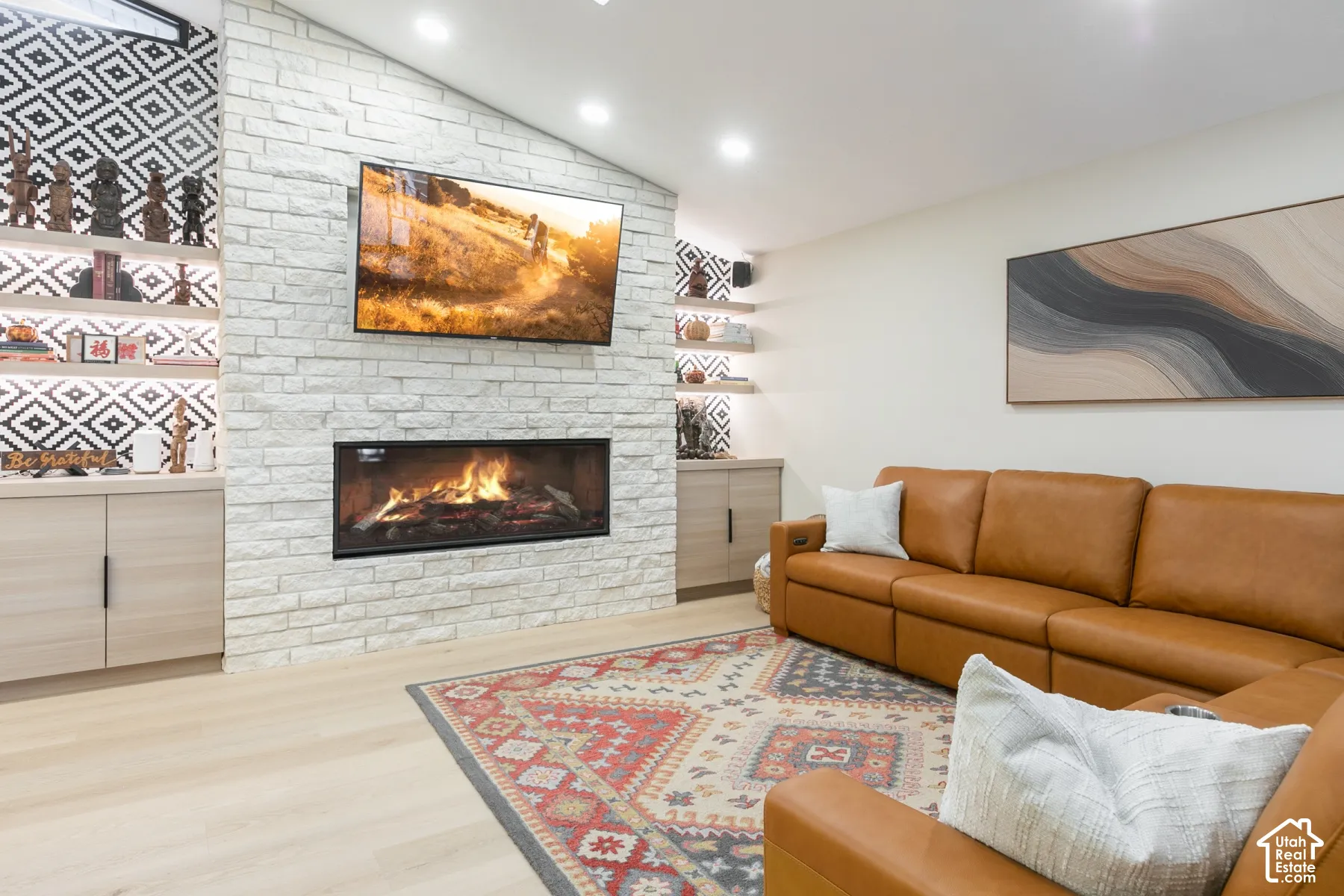 Stone fireplace surround with a linear firebox, wood-finish flooring, and built-in cabinetry with integrated shelving