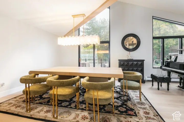 Vaulted ceilings, large floor-to-ceiling windows, light-tone wood-finish flooring, and a modern linear pendant light fixture