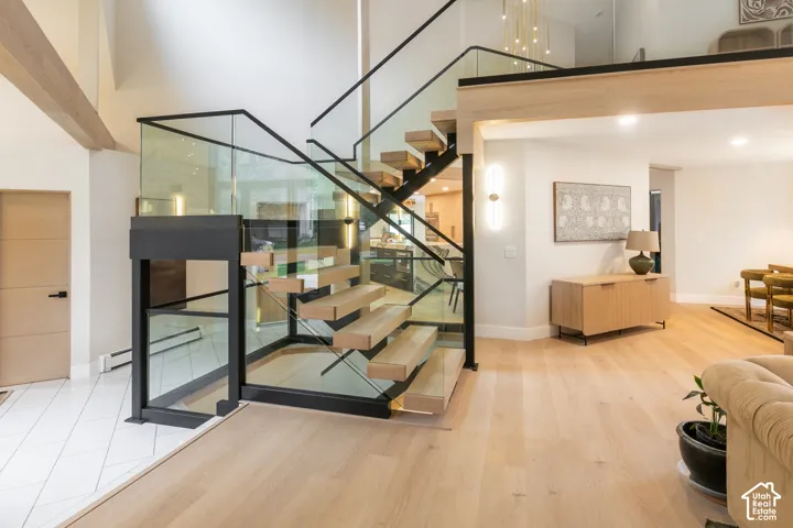 Open-riser staircase featuring natural wood treads, black metal stringers, and tempered glass railings with a matching black metal frame