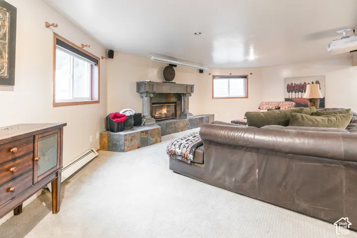 Fireplace featuring a stone tile surround, tiered hearth, and mantle, paired with a motorized retractable projector screen and recessed ceiling lighting