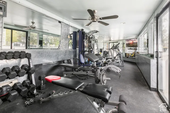 Recreational space featuring wall-to-wall mirrors, recessed lighting, ceiling fans, rubber flooring, and full-height glass sliding doors
