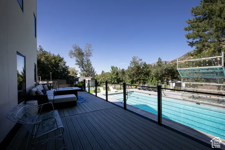 Elevated composite deck featuring a metal cable railing, in-ground swimming pool, and a vertical climbing wall