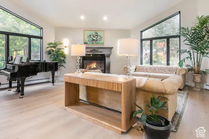 Living area featuring vaulted ceilings, oversized trapezoidal windows, wood-finish flooring, and a decorative fireplace with a carved mantel