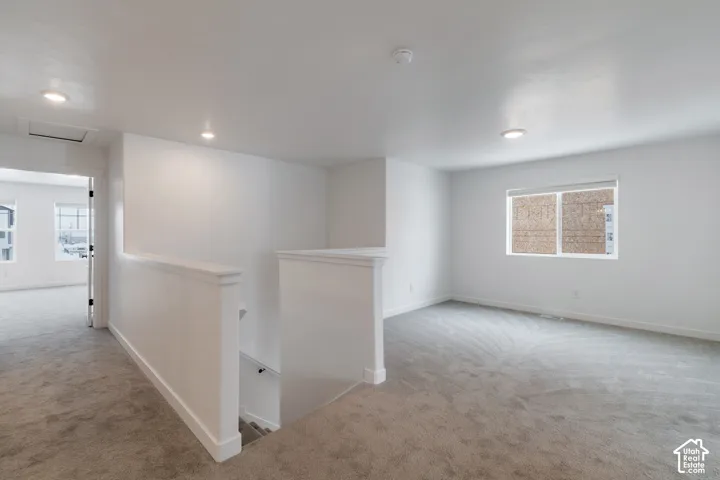 Open-concept area featuring neutral wall-to-wall carpeting, recessed ceiling lighting, and crisp white walls