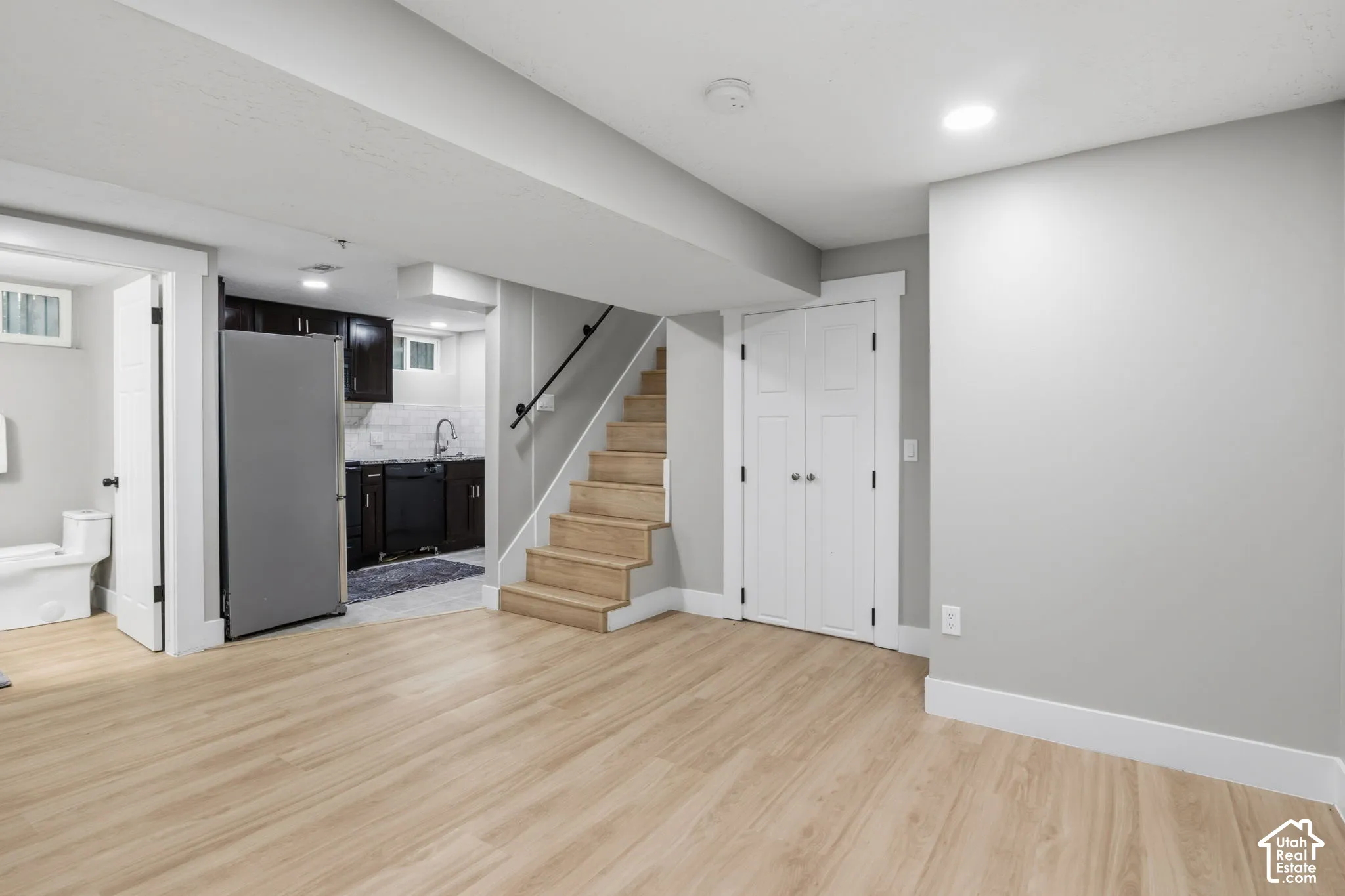 Open interior featuring wood-finish flooring, recessed lighting, a kitchenette with dark cabinetry, and an enclosed storage closet with double doors