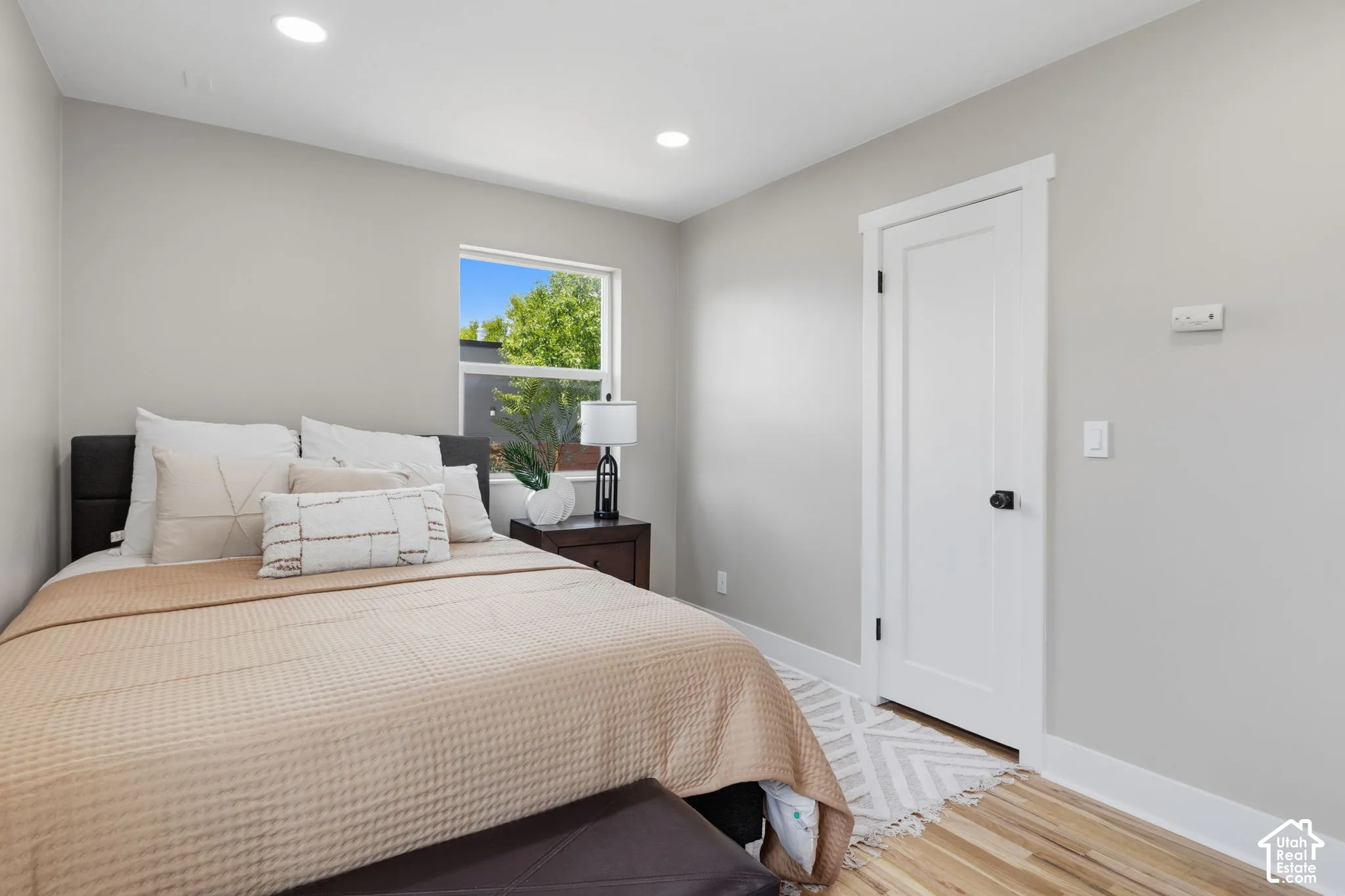 Neutral-toned interior featuring recessed lighting, wood-finish flooring, and a single-panel interior door with matte black hardware
