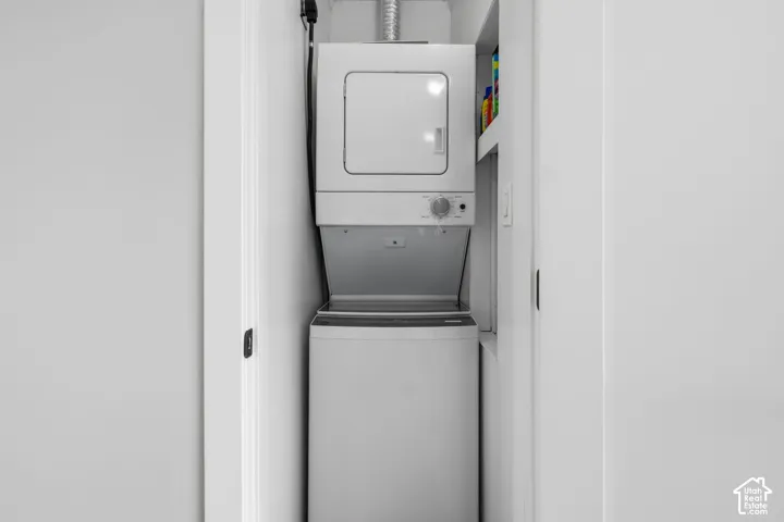Stackable white laundry unit housed in a dedicated closet featuring built-in shelving