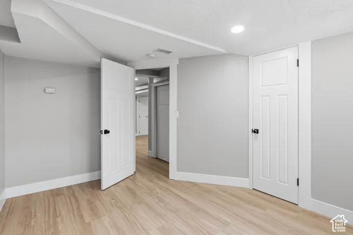 Wood-finish flooring, neutral wall tones, recessed lighting, and white three-panel interior doors with matte black hardware
