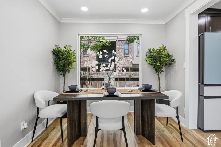 Dining area featuring wood-finish flooring, crown molding, recessed lighting, and a large picture window