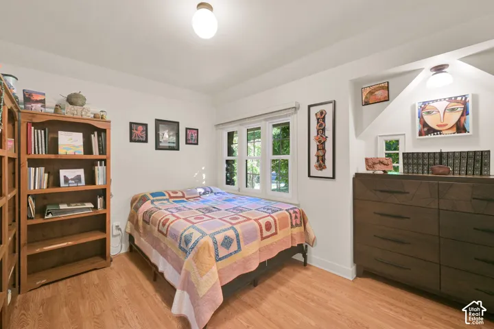 Room featuring wood-finish flooring, a multi-pane window assembly, and a recessed wall alcove with integrated lighting