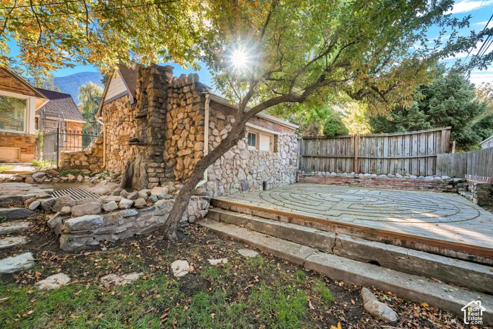Exterior stone masonry, stamped concrete patio with intricate inlay design, stone retaining walls, and tiered concrete steps