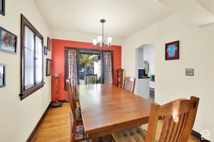 Dining area featuring wood-finish flooring, dark wood-stained window trim, an arched doorway, and a multi-arm chandelier
