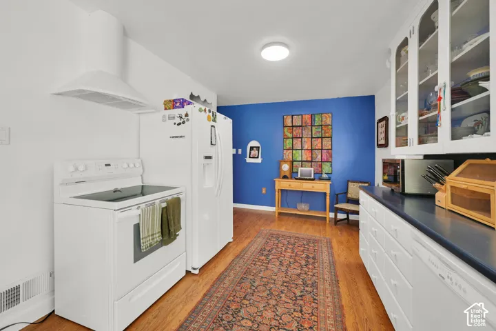 Kitchen featuring wood-finish flooring, white cabinetry, built-in glass-front upper storage, and a range hood