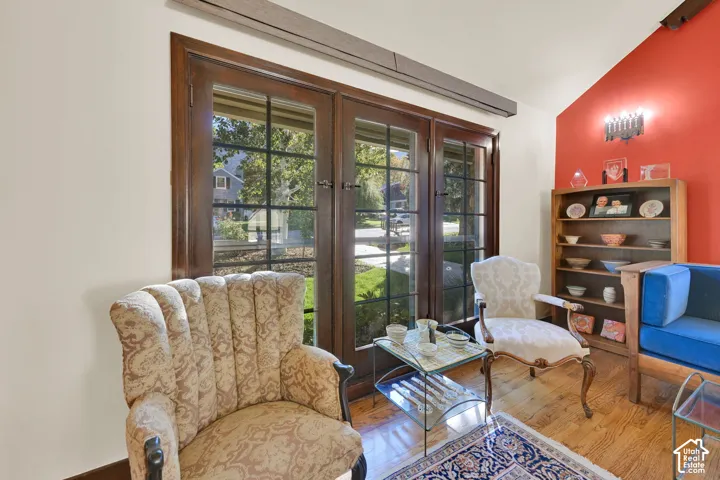 Multi-pane French doors with dark wood frames, vaulted ceiling, built-in shelving, and wood-finish flooring