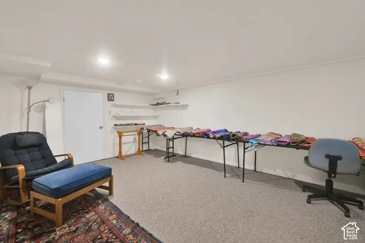 Neutral-toned room featuring wall-to-wall carpeting, white walls, recessed ceiling lighting, and built-in wall shelving
