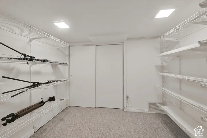 Storage space featuring custom white wire shelving, wall-to-wall carpeting, dual sliding closet doors, and recessed lighting