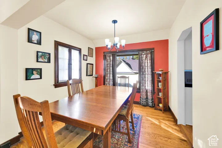 Dining area featuring wood-finish flooring, dark-stained wood window casing, and a multi-light pendant fixture
