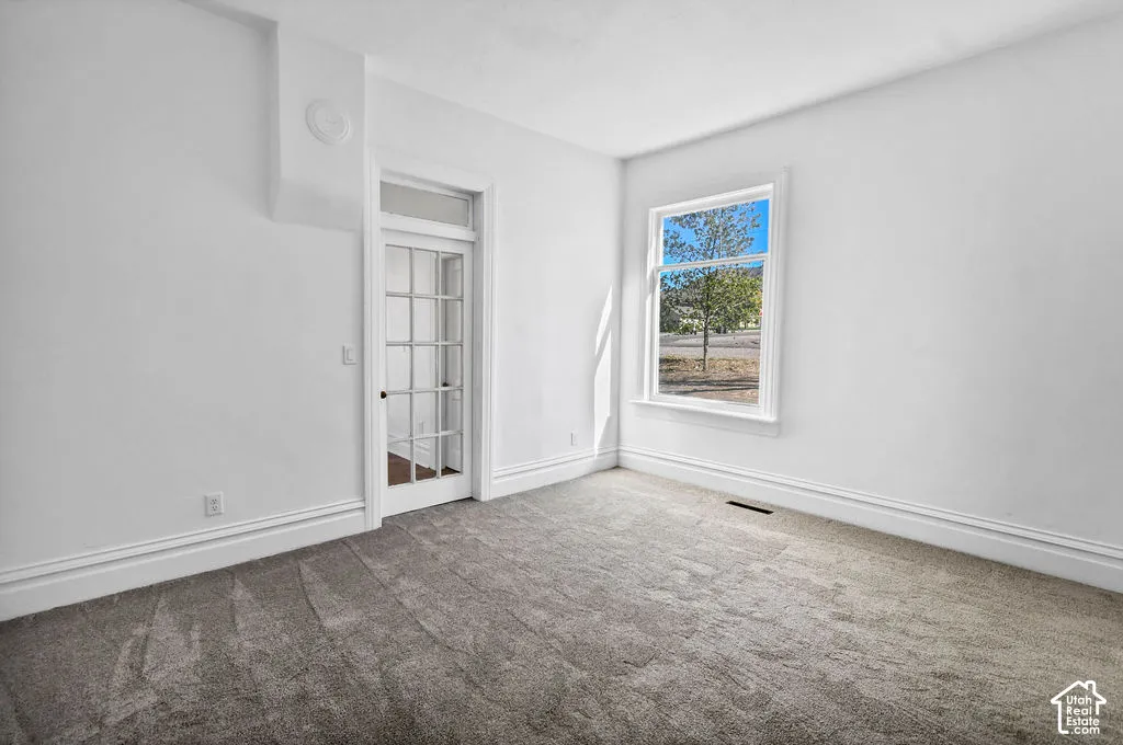 Neutral interior featuring plush wall-to-wall carpeting, a multi-pane glass door with a transom window, and a large window with exterior landscape imagery