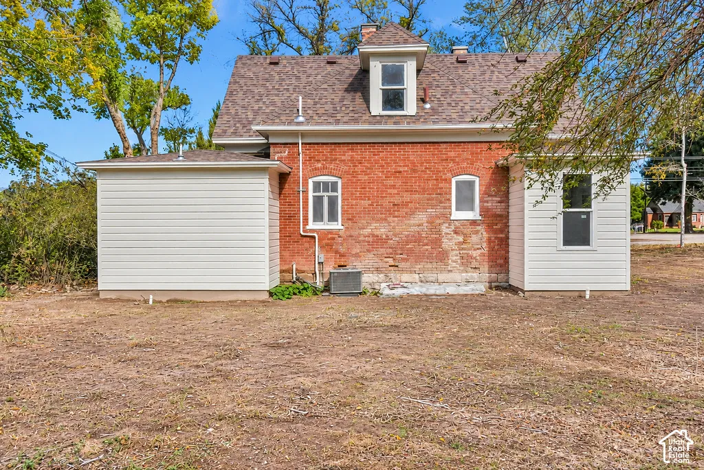 Exterior featuring a red brick facade, horizontal siding, a gabled roofline with a dormer, and multiple windows