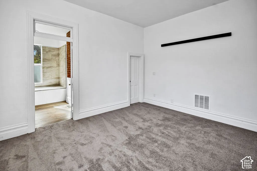 Interior room featuring neutral carpeting, high ceilings, millwork door casing, and a rectangular transom window