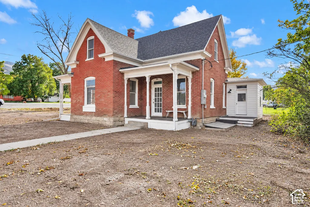Brick exterior featuring a gabled roofline, covered front porch with decorative millwork, and a concrete pathway