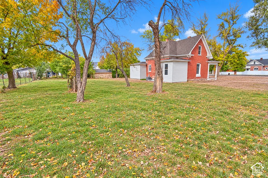 Expansive grounds featuring mature trees, a manicured lawn, red brick exterior, and a white-paneled addition