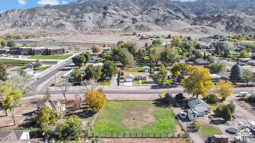 Aerial perspective featuring a spacious vacant lot, mature trees, and mountainous terrain in the backdrop