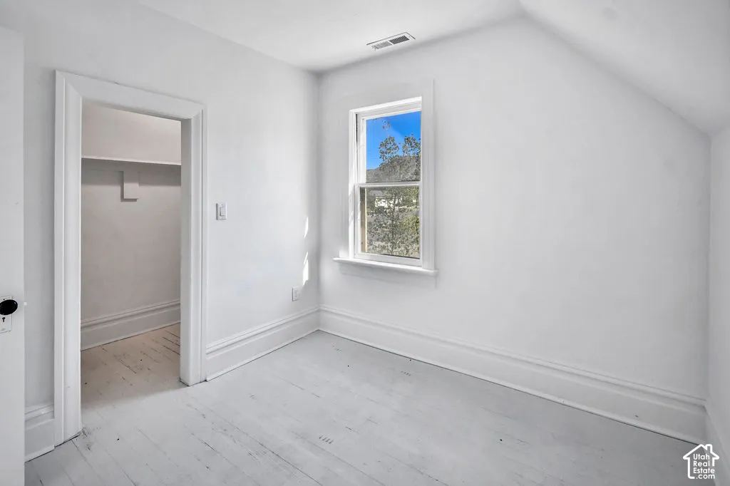 Painted wood flooring, neutral wall finishes, single-hung window with natural light, and walk-in closet with built-in shelving