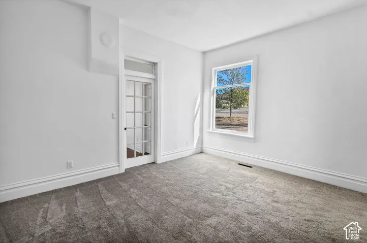 Neutral interior featuring plush wall-to-wall carpeting, a multi-pane glass door with a transom window, and a large window with exterior landscape imagery
