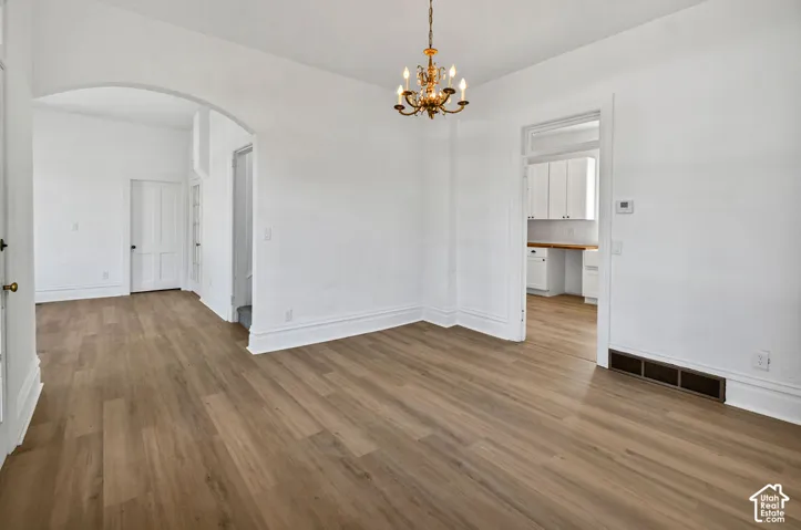 Interior space featuring wood-finish flooring, a rounded architectural archway, and a multi-arm metallic chandelier