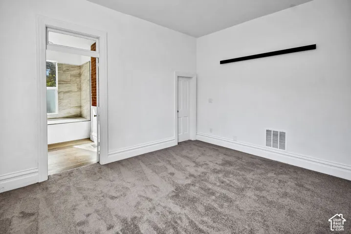 Interior room featuring neutral carpeting, high ceilings, millwork door casing, and a rectangular transom window