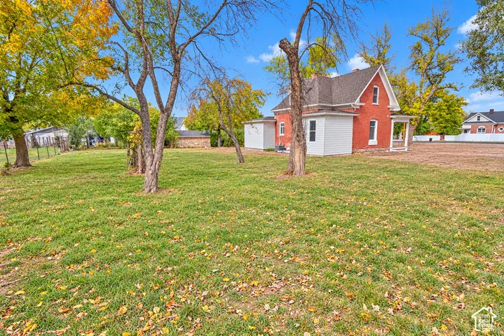 Expansive grounds featuring mature trees, a manicured lawn, red brick exterior, and a white-paneled addition
