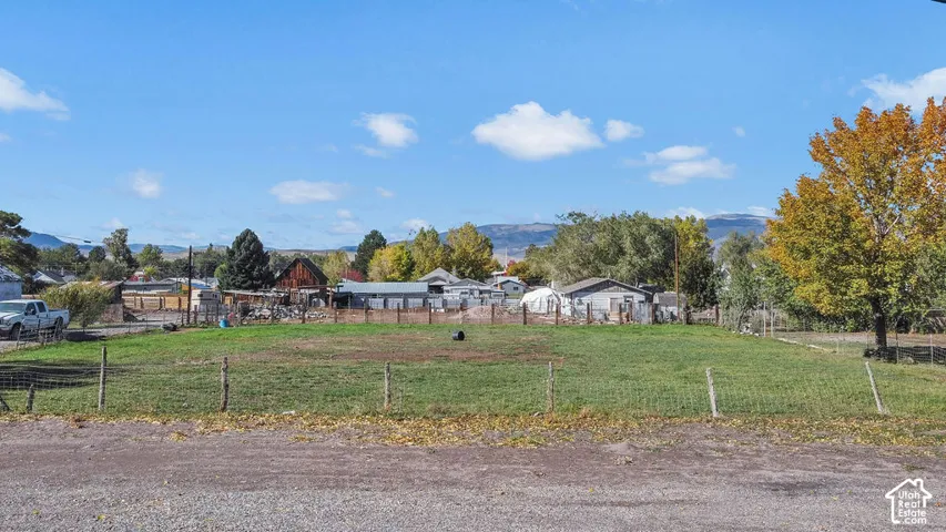 Open, level parcel enclosed by wire fencing with mature trees and mountain scenery