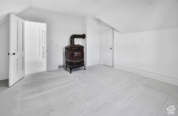 Vaulted ceilings, painted wood-plank flooring, and a decorative cast-iron stove